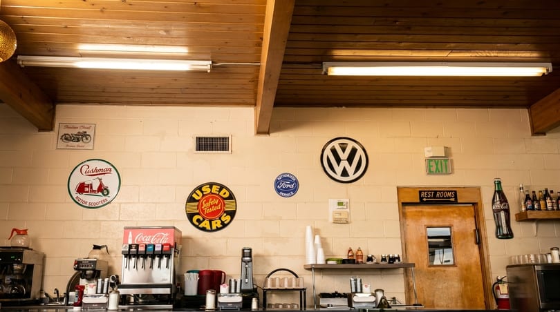 A retro-themed restaurant counter with vintage car and scooter signs on a brick wall.